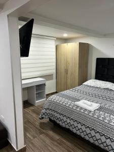 1 dormitorio con 1 cama y escritorio con TV en Apartaestudio en Bogota., en Bogotá