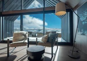 a living room with two chairs and a table and windows at Snow Gum in Mount Hotham