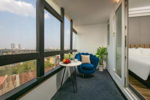 Cette chambre comprend un lit et une table avec une chaise bleue. dans l'établissement Ja Cosmo Hotel and Spa, à Hanoï