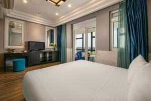a bedroom with a large white bed and a television at Ja Cosmo Hotel and Spa in Hanoi