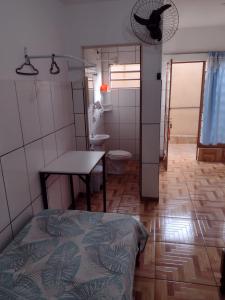 ein Bad mit einem Bett, einem Tisch und einem WC in der Unterkunft Hospedagem A Vale Verde in Londrina