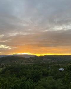 a view of a sunset from a hill with trees at ภูคำฮ้อมคลิฟฟ์ลอดจ์ แอนด์ โฮมสเตย์ Phu come home cliff Lodge & Homestay in Ban Phu Hi