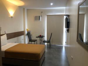 セブシティにある18 Suites Cebuのベッド、テーブル、椅子が備わるホテルルームです。