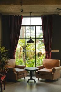 a living room with two chairs and a table and a large window at The Chum Boutique in Hue