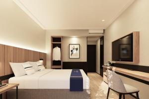 a hotel room with a bed and a flat screen tv at Fieris Hotel & Convention Kertajati in Dawuhan