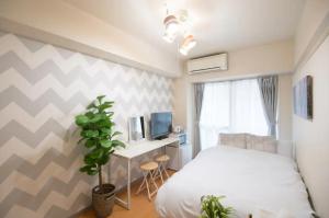 1 dormitorio con 1 cama y escritorio con TV en Hirose inn F+ en Hiroshima