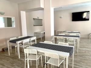 a room with tables and white chairs and a flat screen tv at Pensiunea ALAS in Baile Felix