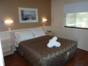 un osito de peluche blanco sentado en una cama en un dormitorio en Reflections Eden - Holiday Park en Eden