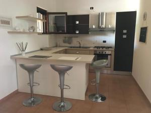 a kitchen with a counter and stools in a room at Il mare di Matera in Policoro +11 photos