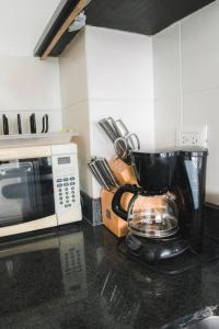 a kitchen counter with a coffee maker and a microwave at Moderno Dpto al pie del mar piscina/jacuzzi in Playas