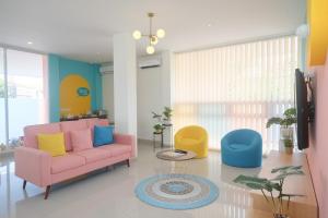 スマランにあるSans Hotel Aurum Semarangのリビングルーム(ピンクのソファ、カラフルな椅子付)