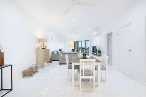 a white living room with a table and chairs at Sleek Penthouse Style meets Stunning Coastal Views in Nightcliff