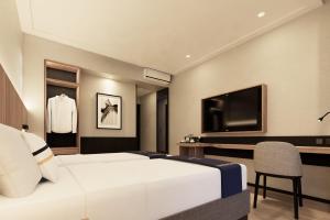 a hotel room with a white bed and a tv at Fieris Hotel & Convention Kertajati in Dawuhan