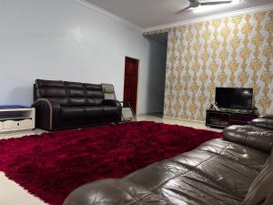 - un salon avec un canapé en cuir et un tapis rouge dans l'établissement VINDRA HOMESTAY, à Bidur