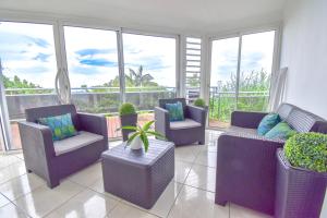 a living room with purple furniture and windows at AU MEUBLE DURANTAS in Petite Île