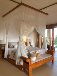 a bedroom with a canopy bed with a basket on a bench at Maya Villa in Candidasa