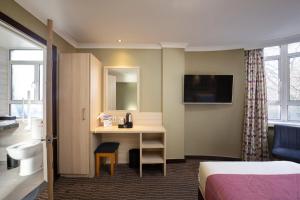 um quarto de hotel com uma cama e uma secretária em President Hotel em Londres