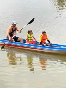 a man and two children in a blue canoe on the water at Green Mango Bungalows in Kampot