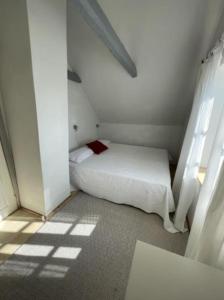 a small white room with a bed and a window at Skønt feriehus midt i Marstal. in Marstal