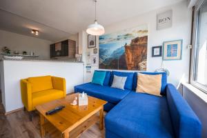 ein Wohnzimmer mit einem blauen Sofa und einem gelben Stuhl in der Unterkunft MOOKI Lake Apartment Ossiacher See&Gerlitzen in Sattendorf