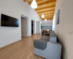 a living room with a couch and a television on a wall at Residence Del Tellaro in Noto Marina