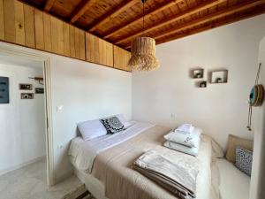 a bedroom with a bed with white sheets and a wooden ceiling at Lux Mykonos house in Agios Stefanos