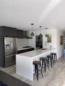 a kitchen with a white counter and some stools at Lakes Executive Suites in Tauranga