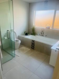 a bathroom with a tub and a toilet and a glass shower at Lakes Executive Suites in Tauranga