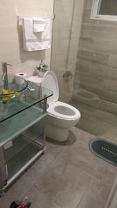 a bathroom with a toilet and a glass table at tropicana sur apt221 in Sosúa