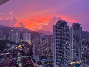 um horizonte da cidade ao pôr-do-sol com edifícios altos em LM HomeyB 3BR Coastline Family Suite for 4-14 Pax with Nexflix & Coway Water Purifier em Tanjong Tokong