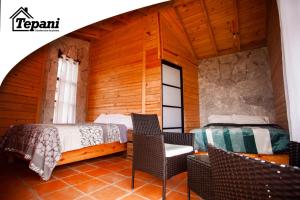 1 Schlafzimmer mit 2 Betten und Stühlen in einem Zimmer in der Unterkunft Cabañas Tepani in Tzicuilán