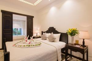 a bedroom with a bed with a cake on it at Hoi An Ancient House Resort & Spa in Hoi An