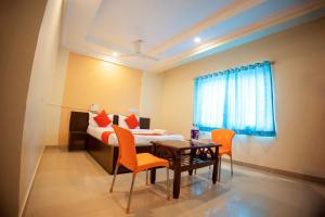 a bedroom with a bed and a table and chairs at Hotel Om Palace in Lonavala