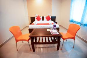 a small room with a bed and a table and chairs at Hotel Om Palace in Lonavala