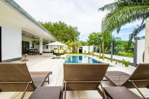 an outdoor patio with chairs and a swimming pool at RUSARDI Poolvilla Ao Nang - new Villa 4 Bedrooms 4 Bathrooms, 10m Pool in Ao Nang Beach