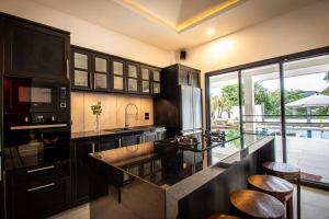 una cocina con armarios negros y una barra con taburetes en RUSARDI Poolvilla Ao Nang - new Villa 4 Bedrooms 4 Bathrooms, 10m Pool, en Ao Nang Beach