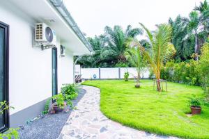 a backyard with a grassy yard with palm trees at RUSARDI Poolvilla Ao Nang - new Villa 4 Bedrooms 4 Bathrooms, 10m Pool in Ao Nang Beach
