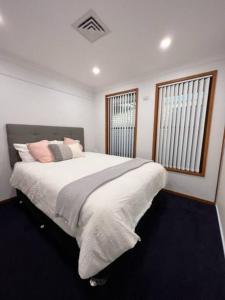 a bedroom with a large bed and two windows at Waterfront Bliss in Port Macquarie