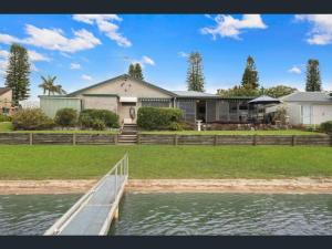 a house with a dock in front of the water at Waterfront Bliss in Port Macquarie