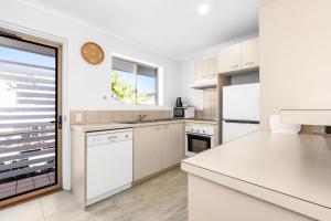 una cucina con elettrodomestici bianchi e un orologio sul muro di 7 Pelican Beach Resort a Noosaville Altre 3 foto