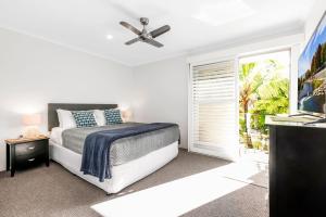 a white bedroom with a bed and a window at 7 Pelican Beach Resort in Noosaville