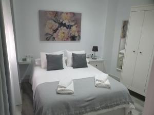 Precioso apartamento con patio interior. في ميدينا سيدونيا: غرفة نوم بيضاء مع سرير عليه منشفتين