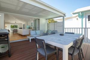 a dining table and chairs on a deck at Banksia in Blueys Beach