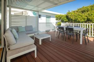 a patio with a couch and a table on a deck at Banksia in Blueys Beach