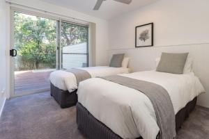 two beds in a room with a window at Banksia in Blueys Beach