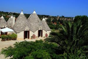 a building with pointed roofs with a palm tree at Masseria Peppeturro in Cisternino