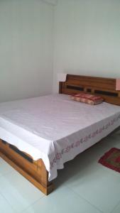 1 dormitorio con 1 cama con marco de madera en Sandaru Hotel & Homestay, en Katugastota