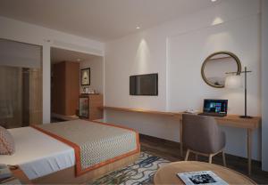 um quarto de hotel com uma cama e uma secretária com um computador em Bellevue Sarovar Premiere Junagadh em Junagadh