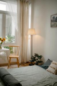 um quarto com uma cama, uma cadeira e uma janela em La Maison em Ấp Tân An (2)
