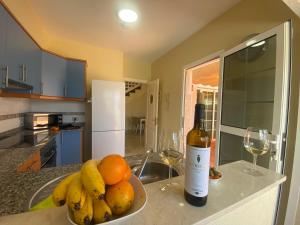 Uma garrafa de vinho e uma taça de fruta no balcão da cozinha. em Apartment With Jacuzzi and pool access em Porto Rico